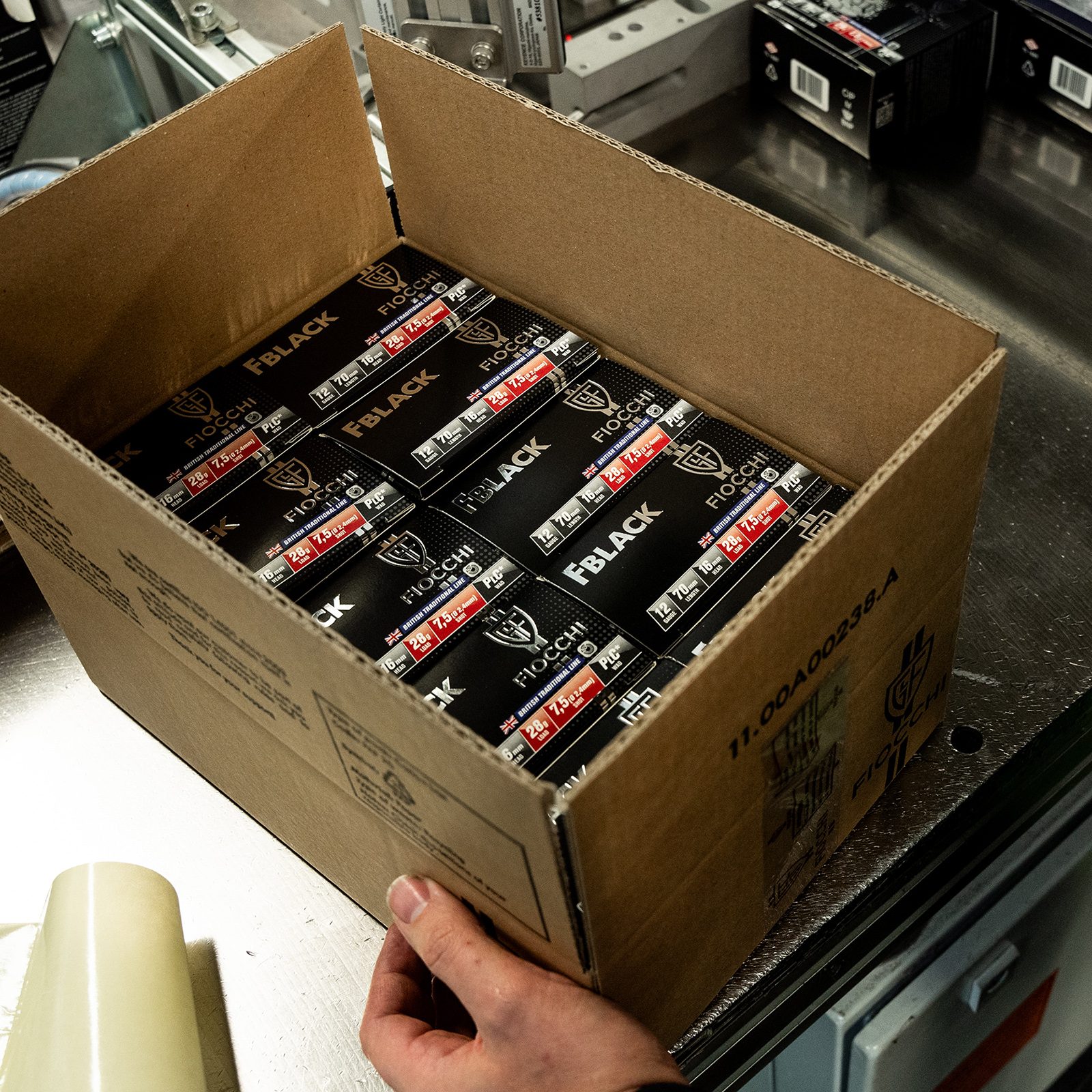 A boxed case of Fiocchi FBlack 12-gauge British Traditional Line cartridges, 28g 7.5 shot, being lifted off a factory line.
