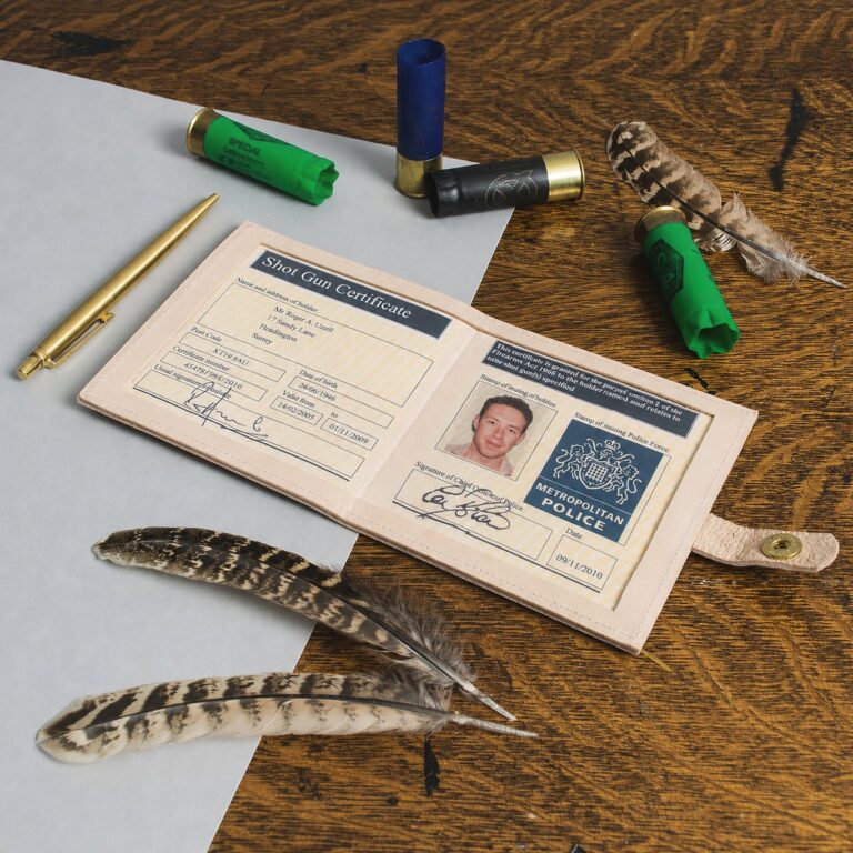 A shotgun certificate open in its wallet on an oak table, with cartridges, a pen and partridge feathers