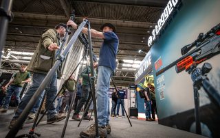 Visitors handling tactical tripods on the 3 Legged Thing stand at the Great British Shooting Show