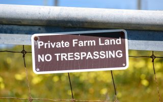 A "private farm land, no trespassing" sign fixed to a field gate.
