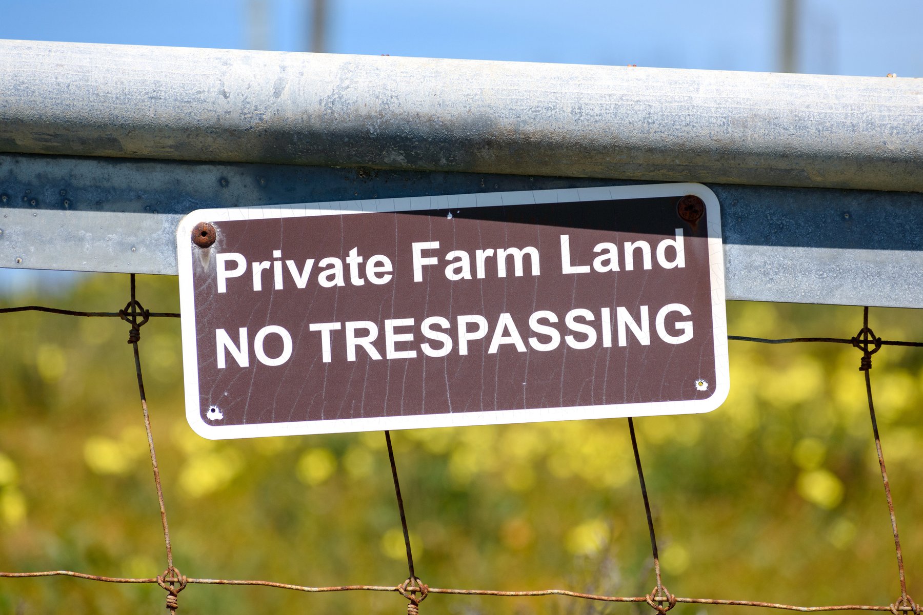 A "private farm land, no trespassing" sign fixed to a field gate.
