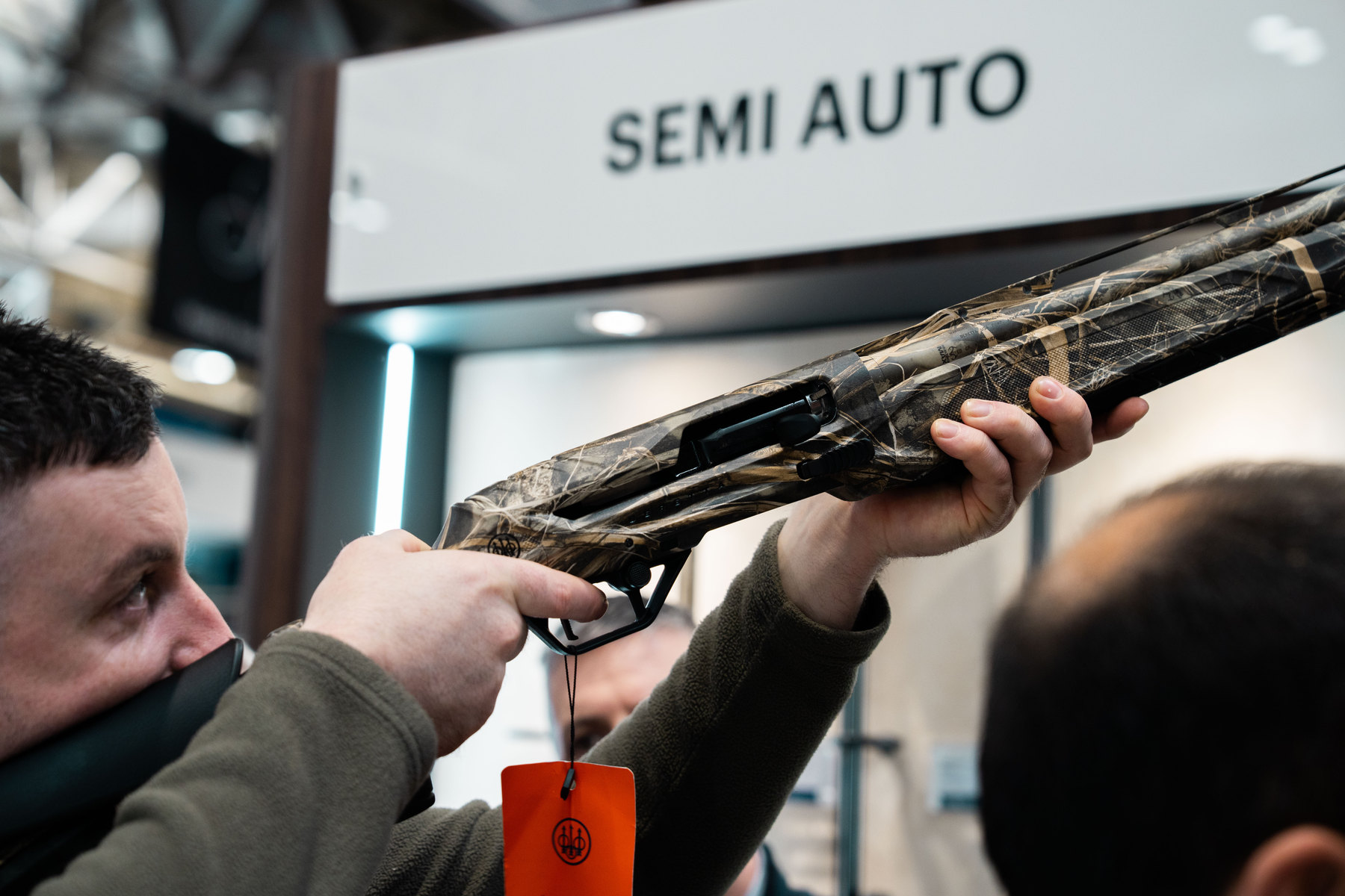 A visitor mounting a camouflage-finish Beretta semi-automatic shotgun on the GMK stand