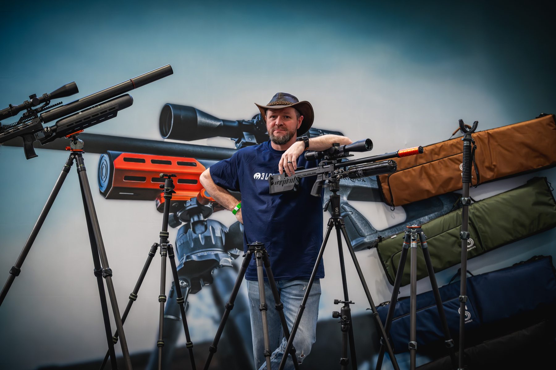Danny Lenihan of 3 Legged Thing with a rifle on a tactical tripod on the company's stand at the NEC
