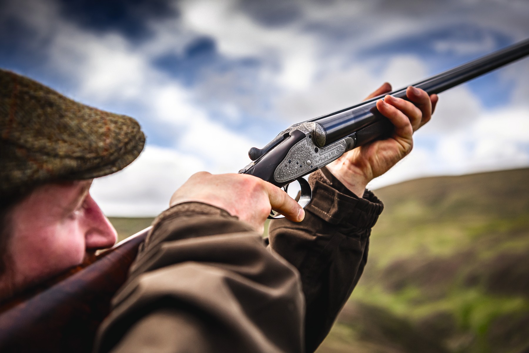 A Gun mounting a side-by-side shotgun on a hillside under a cloudy sky