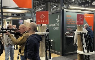 The Swarovski Optik and Kahles stand at the 2026 British Shooting Show, with visitors handling rifles and optics
