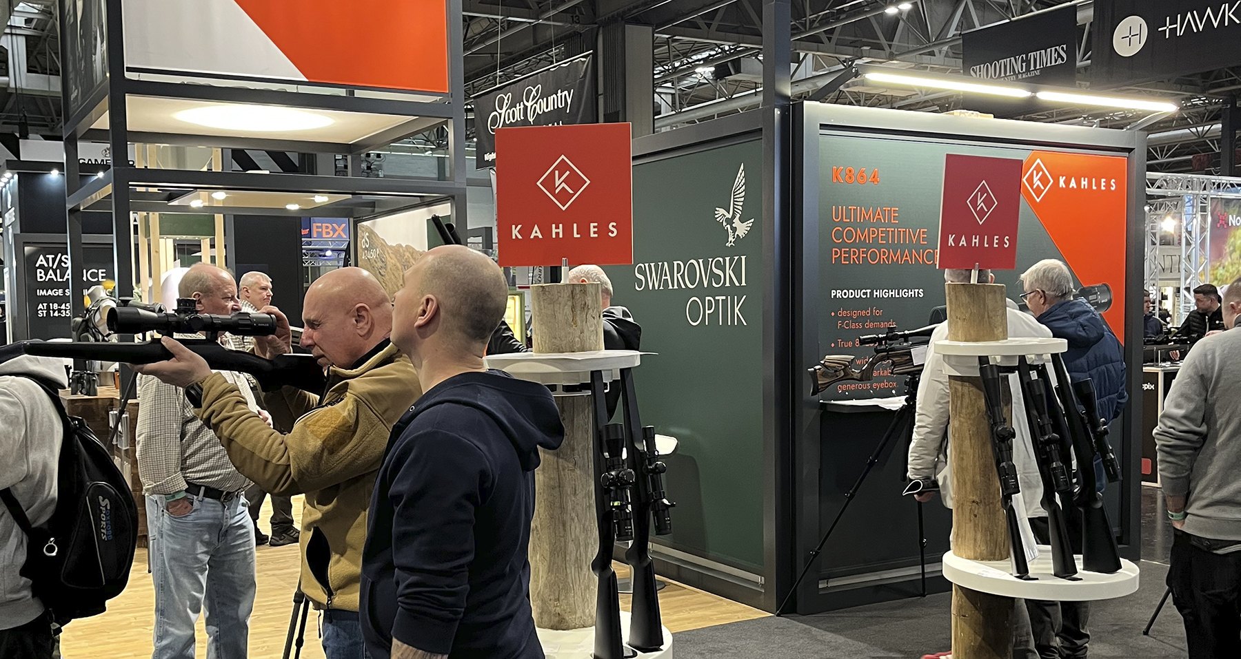 The Swarovski Optik and Kahles stand at the 2026 British Shooting Show, with visitors handling rifles and optics