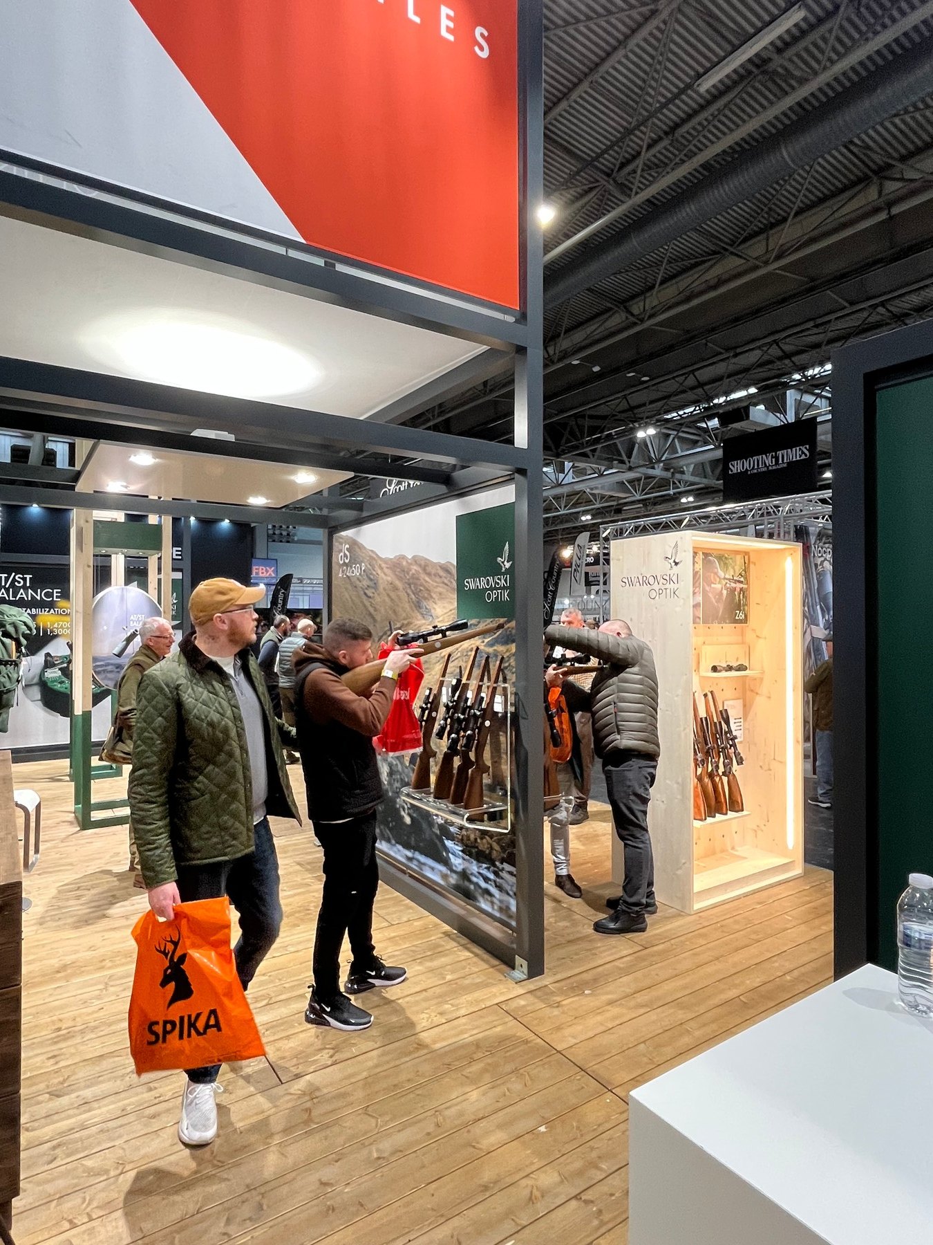 Visitors at the rifle rack on the Swarovski Optik stand, set against a mountain backdrop