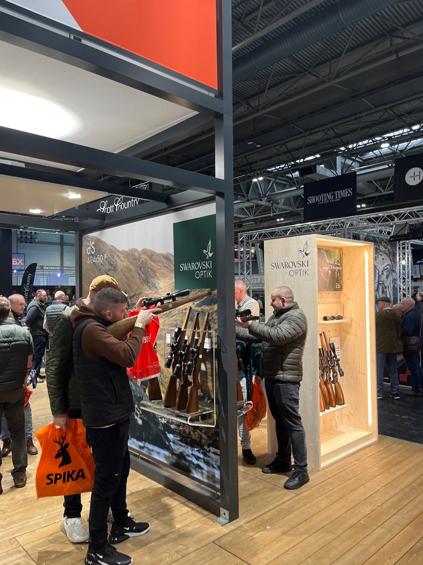 A visitor shouldering a rifle on the Swarovski Optik stand at the British Shooting Show