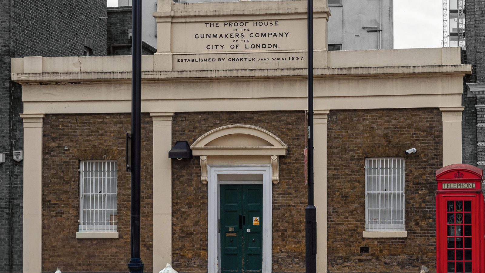 The front of the London Proof House on Commercial Road, with a red telephone box beside it